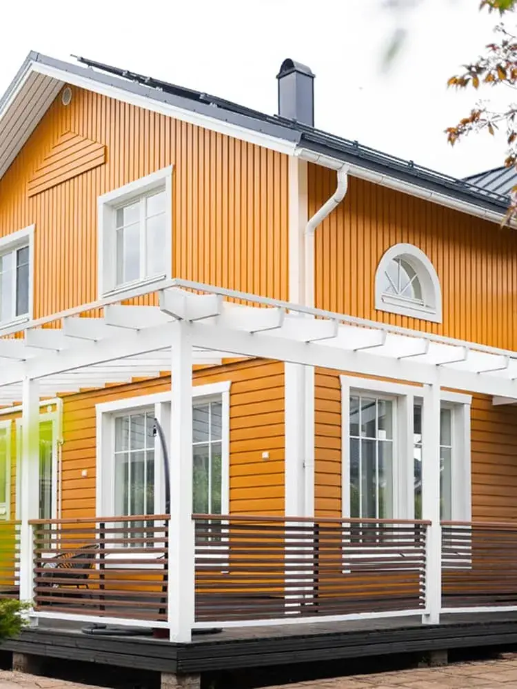 Oranssiksi maalattu puutalo ja valkoinen pergola – Maalauskulma